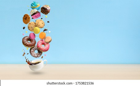 Donuts, cupcakes, cookies, macaroons and coffee cup flying over blue background.Pastries, cakes and coffee cup with splash. Copy space - Powered by Shutterstock