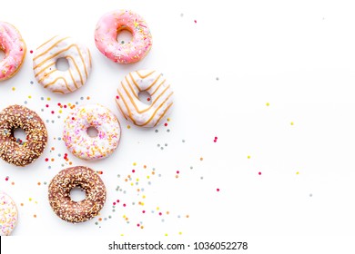 Donuts decorated icing and sprinkles on white background top view copy space pattern