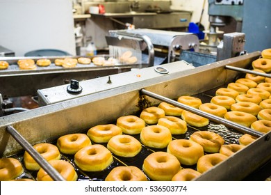 Donuts are fried, glazed, and put on racks in a doughnut shop bakery. 