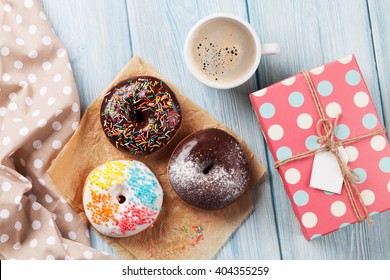 Donuts, Gift Box And Coffee On Wooden Table. Top View