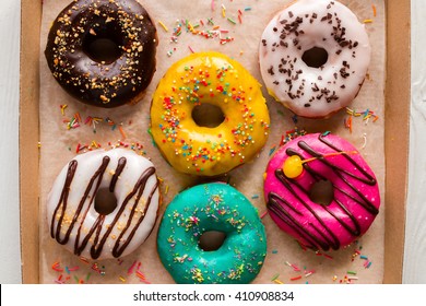 donuts in glaze with sprinkles in a box on a white background