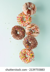 Donuts Glazed With Chocolate And Confectionery Sprinkles In Free Flight On A Light Blue Background. Holiday, Sweet Food, Birthday, Supermarket, Confectionery. Banner.