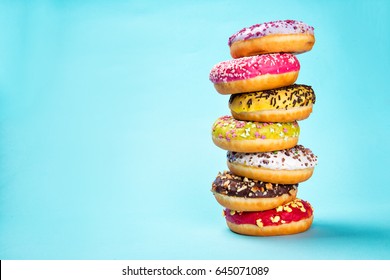 Donuts glazed with sprinkles on pastel blue background, close-up.