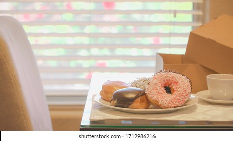 Donuts From A Local Business In Southern Nevada. Placed On A Glass Breakfast Table. Coffee Cup And Cardboard Box To The Side. The Rose Bush Outside The Window Creates A Beautiful Bokeh Background.