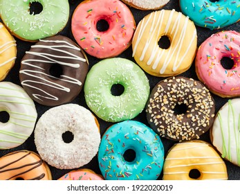 Nimmt ein Muster ab. Draufsicht von verschiedenen Glastüren. Farbige Donuts mit Eis als Hintergrund mit Kopienraum. Verschiedene bunte, verglaste Donuts mit Sprinklen.