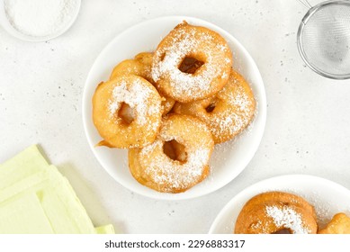 Donuts con azúcar en polvo en placa blanca sobre fondo de piedra clara. Vista superior, posición plana