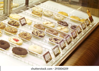  donuts shop,  Display of delicious pastries in a bakery with assorted glazed donuts , biscuits and cookies on trays in a shop counter