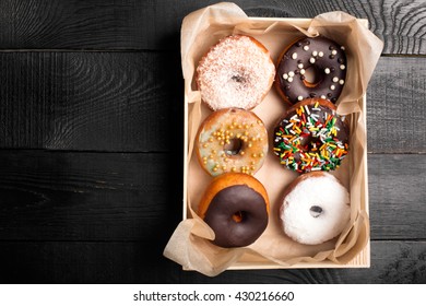 Donuts With Sprinkles In A Wooden Box On A White Table