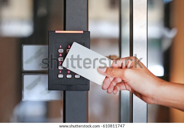 Door access control - young woman holding a key\
card to lock and unlock\
door.