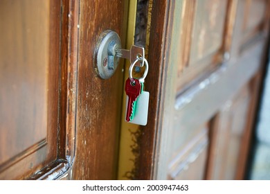door ajar with the key in the lock and a key ring with a red key and a green key