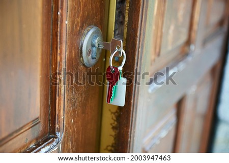 door ajar with the key in the lock and a key ring with a red key and a green key