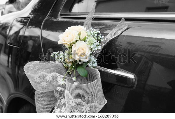 Door of black wedding car decorated with bouquet and\
white bow