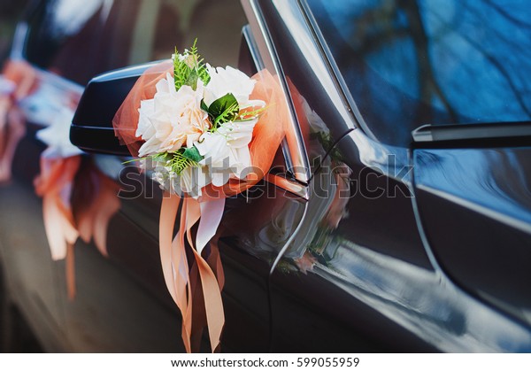 Door of\
black wedding car with flowers and white\
bow