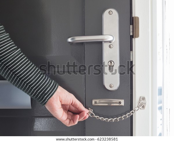 Door chain on a\
grey door, security\
measures