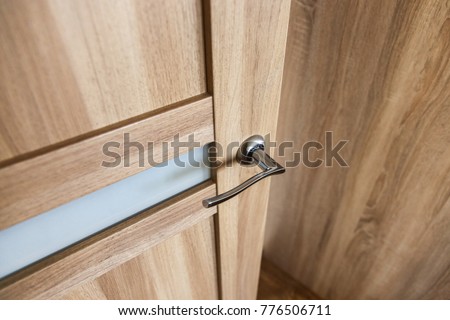 Door handle in the interior.  Knob close-up elements. Open and closed light wooden doors in in modern style in the interior. Door handle, fittings for interior design. Home apartment interior.
