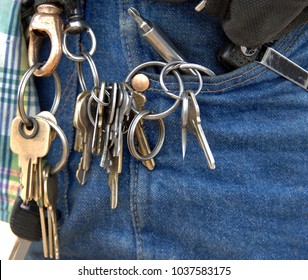 Door keys hang from many loops on a janitors key chain.  He has tools in his pocket and is ready for anything.