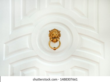 Door knocker with lion. Decorative door handle in form of bronze lion head on white wooden entrance door. antique, gothic, mystery, vintage concept