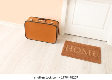 Door mat and suitcase on floor in hallway