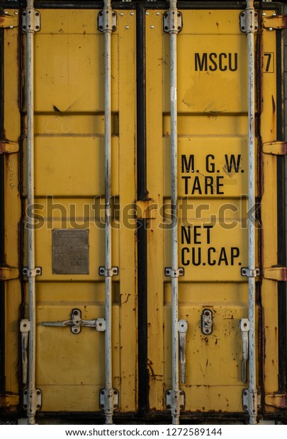The door\
of an old yellow cargo shipping\
container