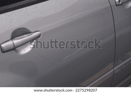 Сar door scratched, damage to paint and lacquer coat. Dent car scratch. Vandal scratched car with nail at parking lot. 
