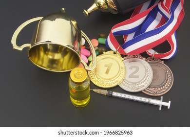 Doping In Sport Concept. Broken Trophy Cup, Medals, Syringe And Drugs On Black Table.