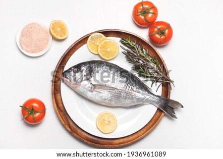 Dorado fish or gilt-head bream served on white plate on white background, flat lay, top view