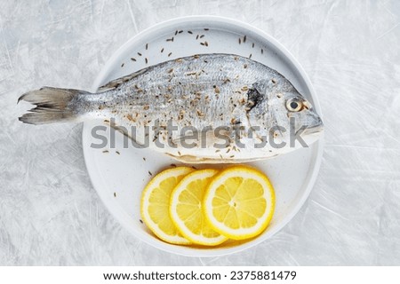 Dorado with lemon and spices on white plate. Seafood concept. Top view