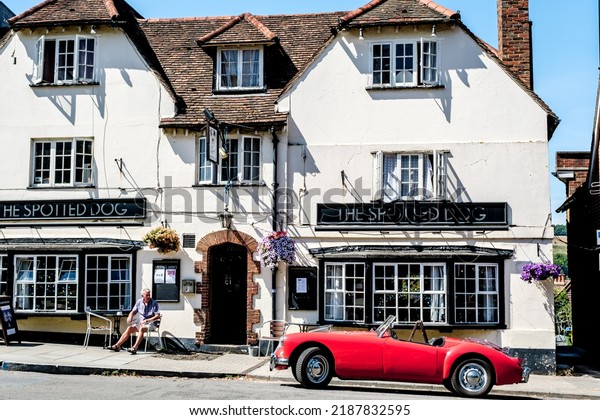 Dorking,
Surrey Hills, London UK, July 07 2022, Red Open Top Classic Sports
Car Parked Outside A Tradition English
Pub