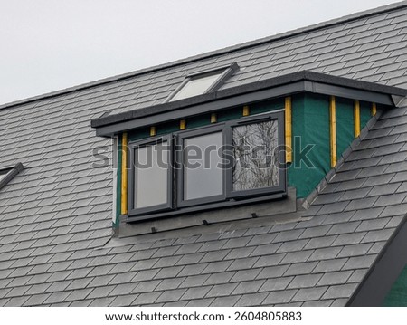 Dormer window under construction in a new slate covered roof as part of a loft extension