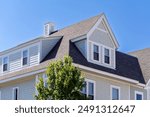 Dormer windows on the sloped shingle roof of a newly built house in Brighton, Massachusetts, USA