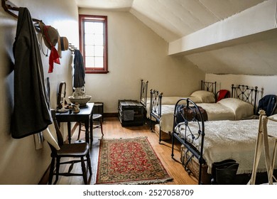 The dormitory loft of the inn in Sovereign Hill town, a cozy and rustic bedroom featuring two twin beds with ornate iron bed frames, vintage linens, and wooden furniture. - Powered by Shutterstock