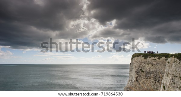 Dorset, England - September 14, 2017: Students on\
a field trip study the prehistoric cliff faces and coastline of the\
English South Coast.