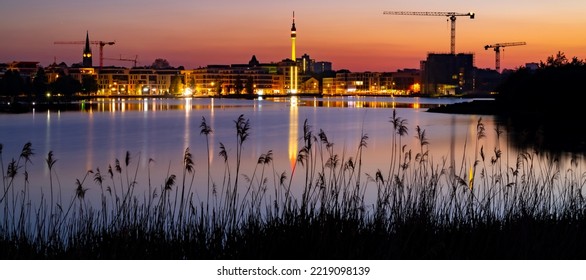 Dortmund Wide Angle Nighttime Panorama. German City With Downtown Skyline, Modern Buildings  And Pond. Evening Sky With Clouds And Reflection In Phoenix Lake At Blue Hour With Colorful Illumination