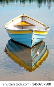 Dory fishing boat reflection in Prince Edward Island blue yellow white boat on clam water