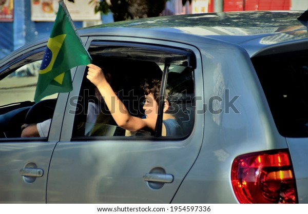 São José dos Campos, São Paulo, Brazil, April\
11, 2021: Child in the car waving a Brazilian flag at the March for\
Family Manifestation for\
Freedom
