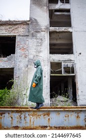 A Dosimetrist Scientist In Protective Clothing And A Gas Mask Checks The Level Of Radioactive Radiation In The Danger Zone. Environmental Pollution, Disaster. Destroyed Houses