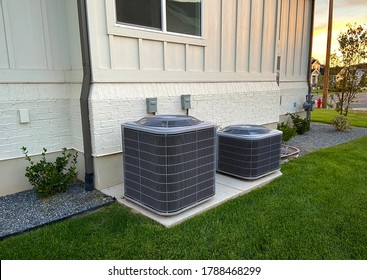 Double AC units outside white brick home with green landscape and gravel - Shutterstock ID 1788468299