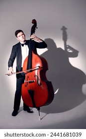 Double bass player contrabass playing. Classical musician man portrait in full length