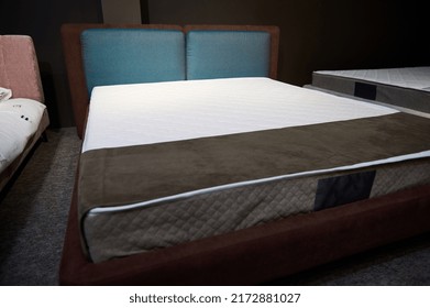 Double bed with orthopedic mattress at the exhibition of upholstered furniture. The exhibition of upholstered furniture for bedroom in a home design studio