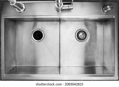 Double Bowl, Drop In Kitchen Sink With Industrial Faucet From Top Down Point Of View With Garbage Disposal Opening And A Drain On Each Bowl Respectively.