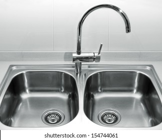 A Double Bowl Stainless Steel Kitchen Sink On A White Granite Worktop