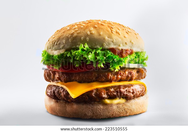 Double burger with cheese, tomato and lettuce\
on white table against white\
background.