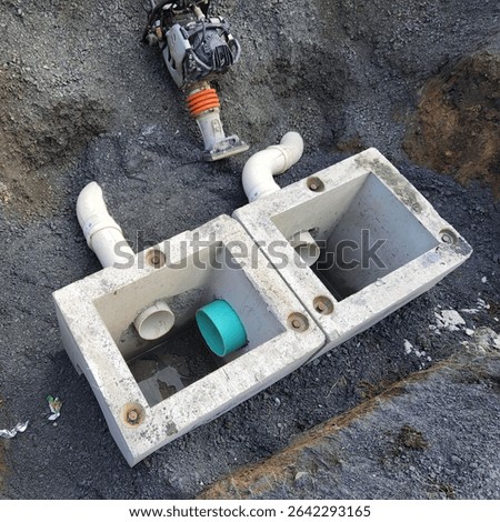 Double Catch Basins with PVC Inlets in Excavated Trench. Two precast concrete catch basins with PVC inlet pipes installed in trench during stormwater infrastructure work.