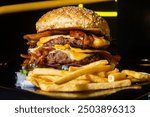 double cheeseburger with fries on black background isolated