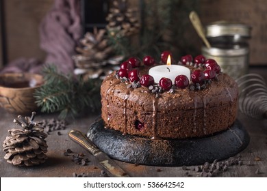 Double chocolate cherry cake with spices and big candle on the rustic background for winter holidays. Christmas and New Year decoration - Powered by Shutterstock