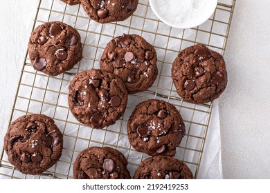 Double chocolate cookies with dark chocolate chips and salt flakes on a cooling rack