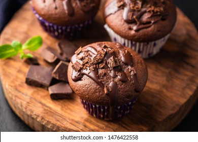 Double chocolate muffins covered with melted chocolate on a wooden background