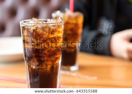 Double cool ice soft drink cola carbonated liquid fresh food with soda water, white dish on wooden table with handsome man sitting  brown sofa in pizzeria restaurant.