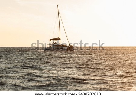 A double cruising catamaran sails at sunset. Evening view and a sailboat off the coast of Lipari in the Aeolian Islands in Italy. Yachting in the Aeolian Archipelago in the Tyrrhenian Sea