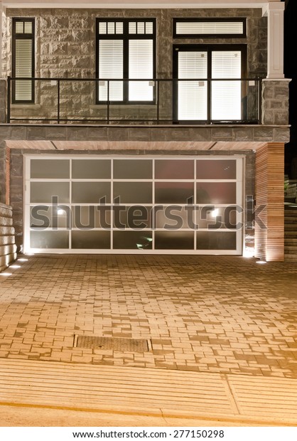 Double doors garage at night, dawn\
time with nicely pawed driveway. North America.\
Vertical.